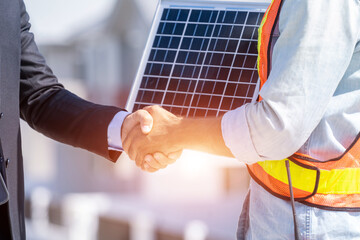 Close up businessman and engineers shaking hands after discussing install solar panels on houses under construction,Renewable energy for residential.