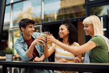 Wall Mural - Young multiracial people toasting to their friendship in cafe.