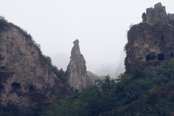 Fog view on the Khndzoresk ancient cave city in the mountain rocks. Armenia landscape attraction. Abandoned ruins in the mist. Atmospheric stock photography.