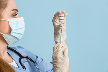 Wall Mural - Female doctor with monkeypox vaccine and syringe on blue background