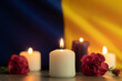 A group of burning candles and flowers on the background of the national flag of Ukraine