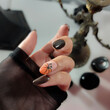 © Vera Bel - Witch woman hands with black nail polish and orange pumpkin design, halloween and all saints manicure