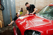 © AS Photo Family - Car service worker put anti gravel film on a red car body at the detailing vehicle workshop. Car protection with special films.