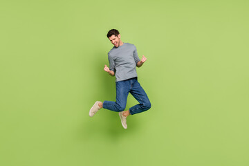 Poster - Full size photo of cheerful laughing man jumping raise fists in success triumph isolated on green color background