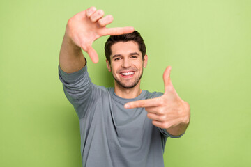 Poster - Photo of nice millennial brunet guy make photo wear grey pullover isolated on green color background