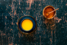 Turmeric Golden Milk On Saucer And Distressed Green Wooden Surface