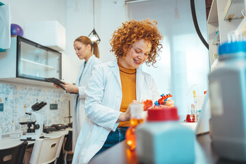 Wall Mural - Modern laboratory interior. Woman working on medical samples in background. Young female scientist standing in her lab. Young Female Scientist Working in The Laboratory