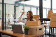 © Natee Meepian - Happy asian woman owner startup small business working on laptop with box at home prepare parcel delivery.