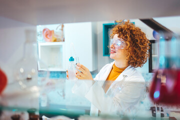 Wall Mural - Scientist looking at test tube in the laboratory at the university. Laboratory assistant analyzing a sample. Scientist / researcher team conducting scientific research in science lab.