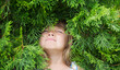 Relaxed child girl in thuja branches breathing fresh air with green branches in background. Aromatherapy and Spa concept. ecology. Earth Day. climate change