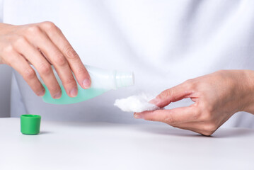   adult woman's hands putting nail polish remover on cotton to clean her nails, manicure at home, health and body beauty.