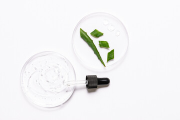 Petri dishes with Aloe Vera cosmetic gel and pieces of Aloe Vera plant, glass dropper and serum bottle on white background top view. Cosmetic laboratory concept. Natural skin care products.