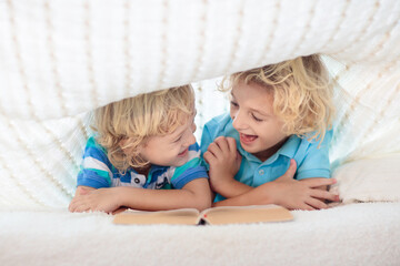 Wall Mural - Child reading book in bed. Kids read books.