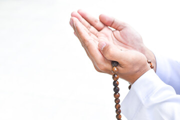 Muslim man in white session lift two hand for praying and wearing bead on hand to determine the number of prayer services.concept for Ramadan, Eid al Fitr, eid ad-ha, meditation, islamic praying