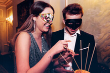 Couple In Masquerade Masks Eating Melon During Party