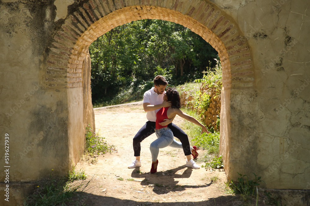 Attractive young couple dancing sensual bachata under an ancient stone ...