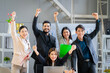 © SKW - A group of young businessmen in suits, Asians, are determined and excited about their work. and encourage the team members by raising their hands happily