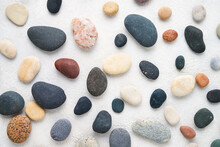 Set Of Colorful Sea Stones On White Concrete Backdrop. Top View, Abstract Background