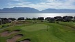 Wide aerial of beautiful Utah golf course with lake and mountains in background 