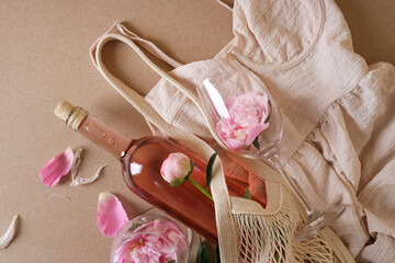 Sticker - Flat lay composition with rose wine, mesh bag, dress and beautiful pink peonies on brown background