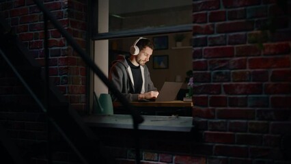 Aufkleber - Software Developer Programming on a Laptop Late Night. Male Specialist Browsing Internet, Listening to Podcast, Does Creative Marketing. Remote Work from Home Concept. View From Outdoors into Window.