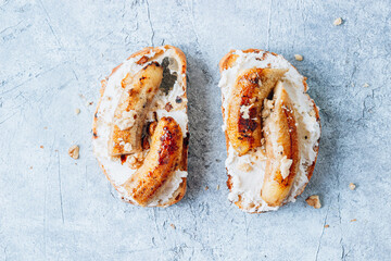 Wall Mural - Fried Caramel Banana Sandwich with nuts and cream cheese on blue concrete background.