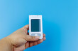 © olyasolodenko - Digital glucometer in female hand over a pastel blue background. Diabetes concept