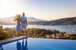 Loving couple on vacation time enjoys the summer sunset over the Aegean Sea by the swimming pool, Greece