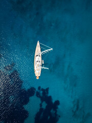 Wall Mural - aerial top down view of a luxurious sailing yacht over turquoise sea