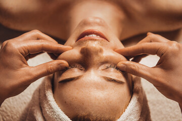 Wall Mural - massage therapist is doing manual massage on client's face. healthy lifestyle concept. cosmetology c