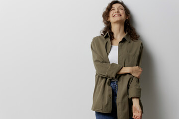 Cheerful happy smiling curly beautiful woman in casual khaki green shirt falling in love touches elbow posing isolated on over white background. People Emotions Lifestyle concept. Copy space