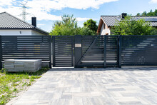 A Modern Panel Fence In Anthracite Color, A Visible Sliding Gate To The Garage And A Wicket With A Letterbox.