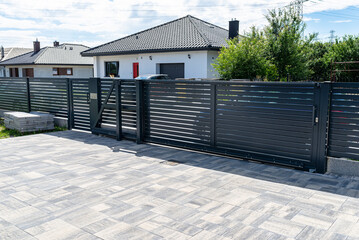 Wall Mural - A modern panel fence in anthracite color, a visible sliding gate to the garage and a wicket with a letterbox.