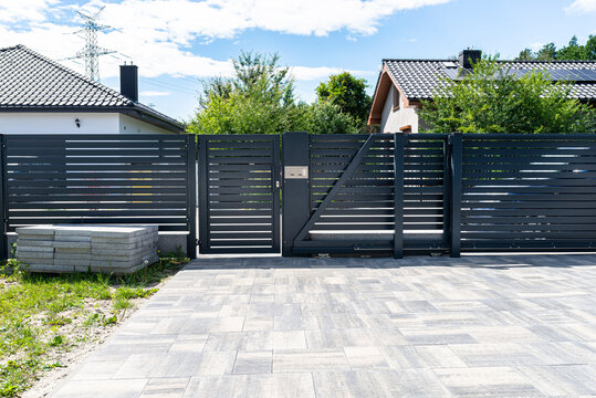 a modern panel fence in anthracite color, a visible sliding gate to the garage and a wicket with a l