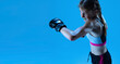 © master1305 - Junior league. Young girl MMA fighter practicing punch isolated on blue background in neon light. Concept of sport, competition, action, achievements