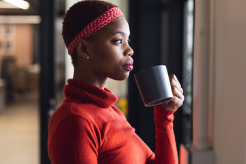 Thoughtful african american businesswoman having coffee while looking away in creative office