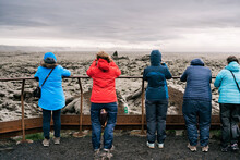 Group Of Anonymous Travelers Admiring Lava Field During Trip In Iceland