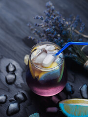 Wall Mural - a glass of lavender lemonade with lemon on a dark table. refreshing craft drink