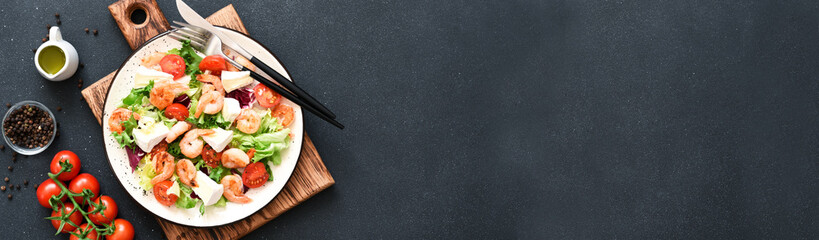 Mix salad with shrimp, brie cheese and tomato sauce on a black concrete background, top view.