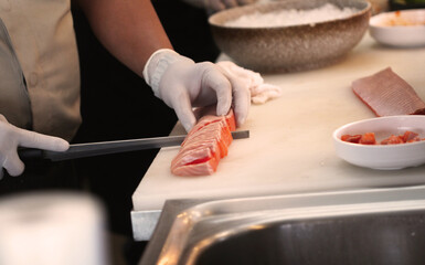 Professional man cut fresh salmon at kitchen of japanese food restaurant.