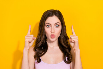 Poster - Portrait of impressed pretty person direct fingers up empty space isolated on yellow color background