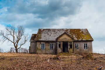 One old abandoned horror wooden house,dramatic stormy clouds with tree at autumn evening.