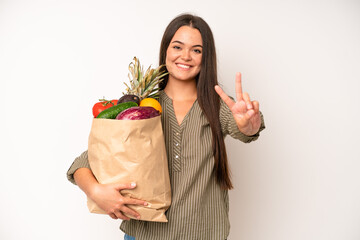 hispanic pretty woma smiling confidently pointing to own broad smile. market vegetables bag concept