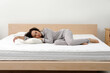 © New Africa - Young African American woman sleeping on bed with comfortable mattress and pillow at home