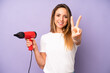 pretty caucasian woman smiling and looking friendly, showing number two. hair dryer concept