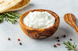 Homemade greek tzatziki sauce in an olibe wood bowl bowl on a light stone background. Close-up, horizontal image, copy space