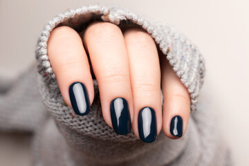 Wall Mural - Female hand in gray knitted sweater with beautiful manicure - dark black nails. Nail care concept