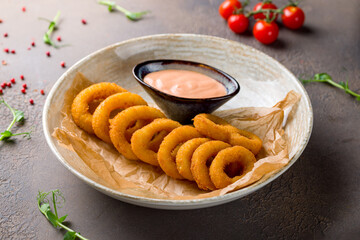 Wall Mural - Rings of squid in batter with coctail sauce on brown table