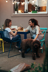 Wall Mural - mother and her teenager daughter sitting table and talking outdoor in home backyard