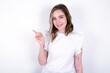 © Roquillo - young caucasian woman wearing white T-shirt over white background points to side on blank space demonstrates advertisement. People and promotion concept
